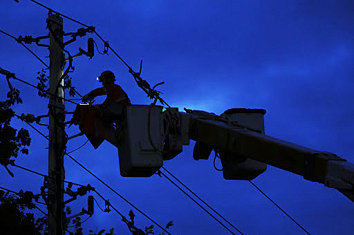 A photo of a hydro worker silhouetted by the night sky.