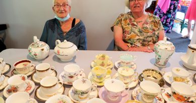 Two people pose with lots of tea cups.