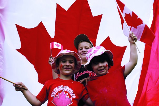 A photo of three kids in front of a Canada Flag.