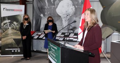 A photo of three people in the Diefenbunker making an announcement.