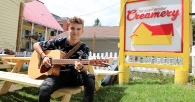 A photo of Carson with his guitar in front of the Carp Creamery.