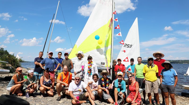 a photo of a group in front of a sailboat.