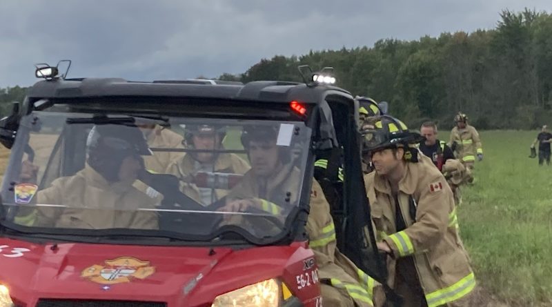 A photo of firefighters surrounding an ATV.