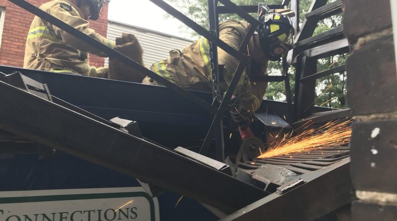 A photo of firefighters cutting a fire escape.