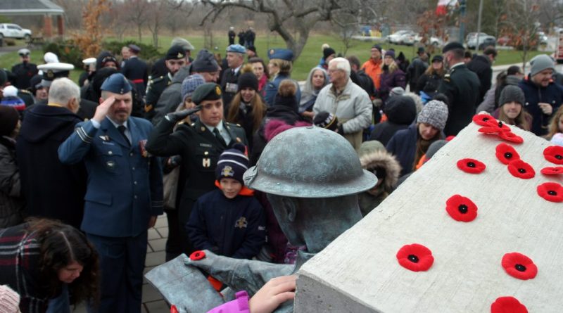 A photo of a group of people around a statue of a soldier at the West Carleton War Memorial.