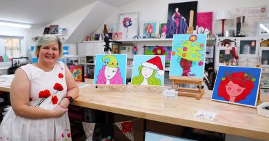 A photo of an artist standing by her art table.