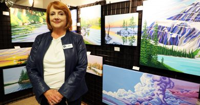 A photo of an artist standing in front of her work.