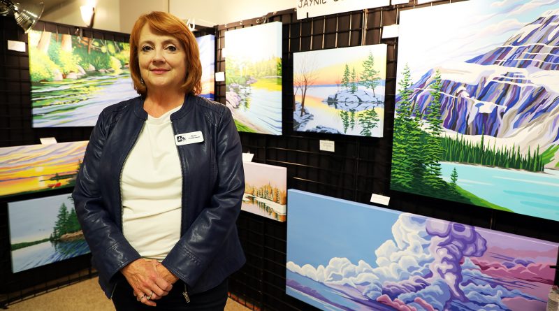A photo of an artist standing in front of her work.