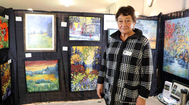 A photo of an artist in front of her work.