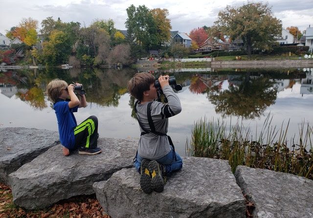 A photo of two kids looking through binoculars.