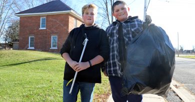 Two boys hold a big bag of garbage.