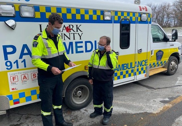 A photo of two paramedics in front of an ambulance.