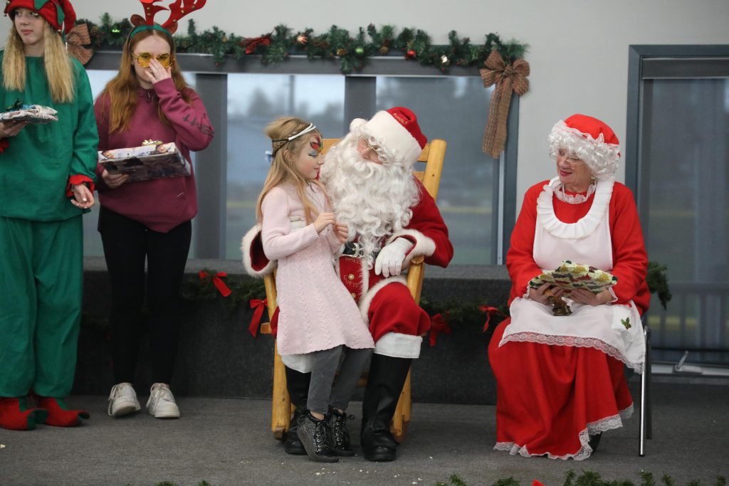 A girl dressed as an angel speaks with Santa.