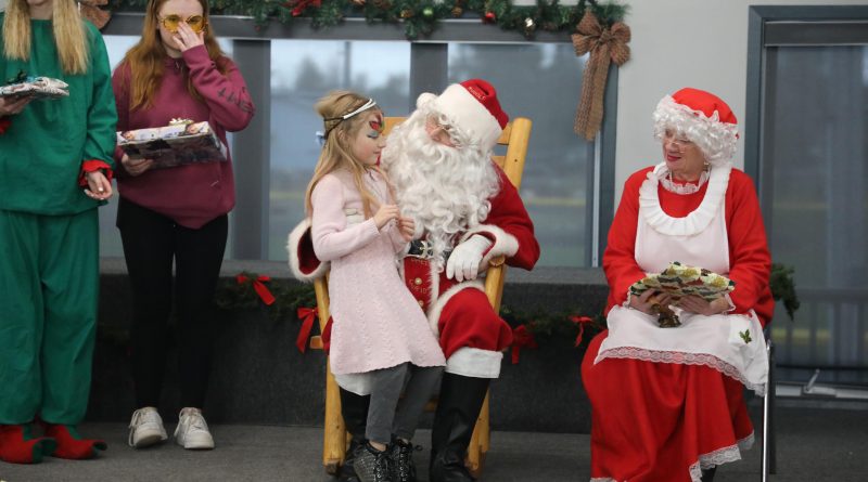 A girl dressed as an angel speaks with Santa.