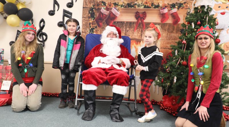 Two kids pose with Santa and a couple of elves.