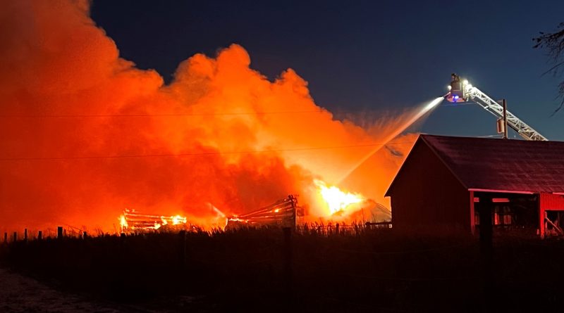 A photo of a large barn on fire.