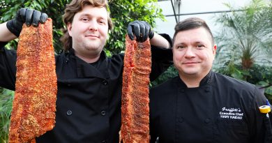 A photo of two chefs holding giant baby back ribs.