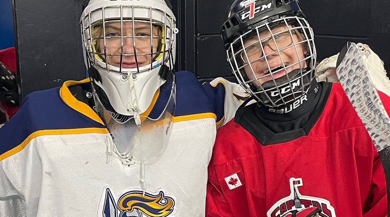 Two brothers pose for a photo in hockey gear.