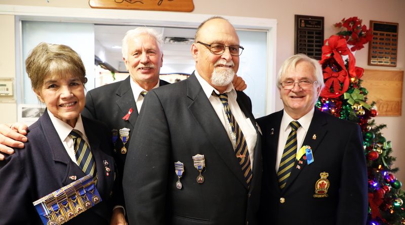 Four Legion members pose in front of a Christmas tree at the branch.