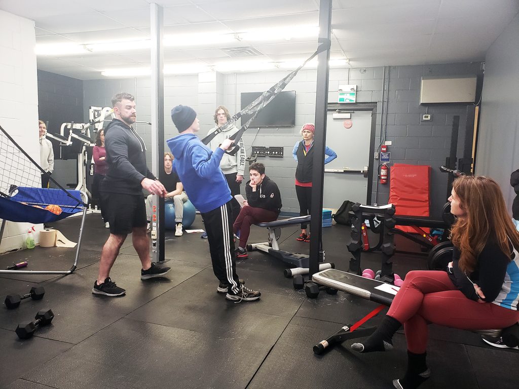 A photo of a gym trainer showing youth how to use the equipment properly.