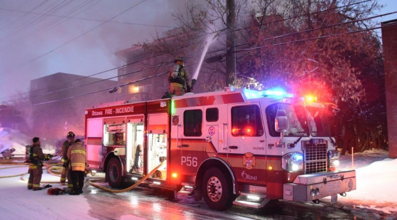 a fire truck sprays down an apartment building.