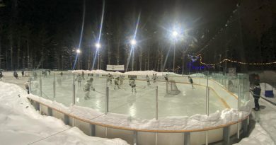A photo of people playing hockey on an outdoor rink.