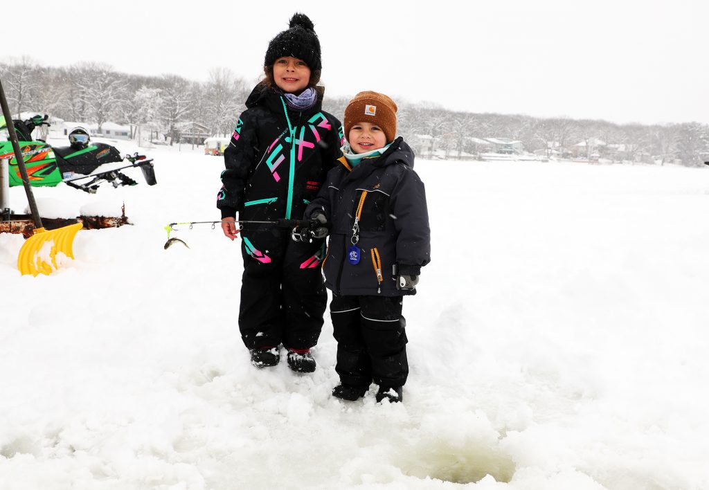 A photo of two kids posing in front of a fishing hole.