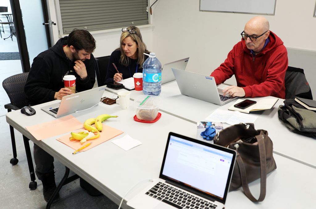 A photo of people working in a room with computers.