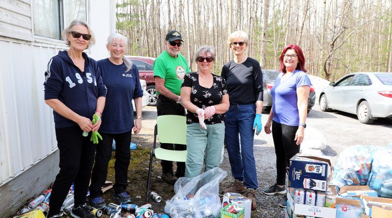 Volunteers pose with a bunch of cans.