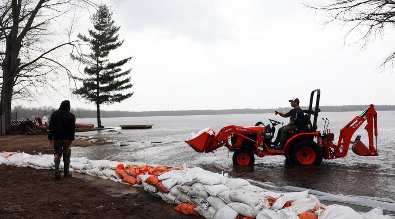 A tractor drives through the Ottawa River delivering sandbags.
