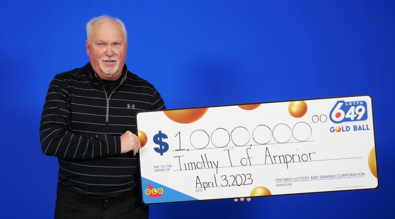 A photo of a man holding a big cheque.