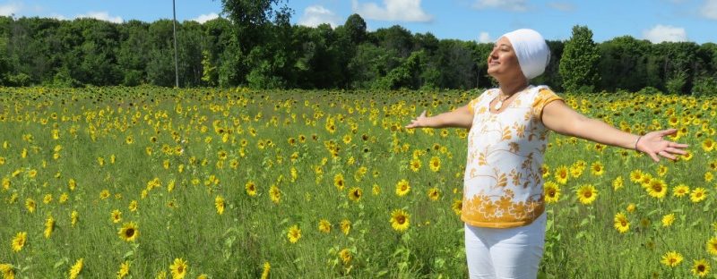 A photo of a yoga instructor standing in a sunflower field.