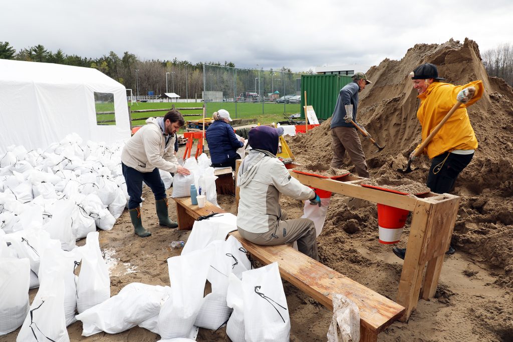 A photo of four people filling sandbags.