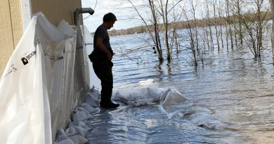 A man works on a sandbag wall in the water.