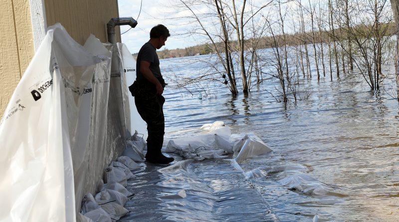 A man works on a sandbag wall in the water.