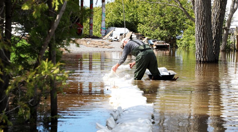 A photo of a man working on a sandbag wall in three feet of water.