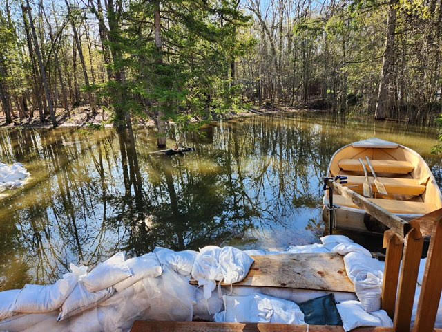 A view from a front door showing water, sandbags and a boat.