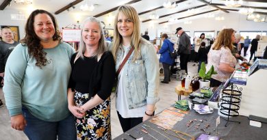 Three people pose for a photo at a craft market.