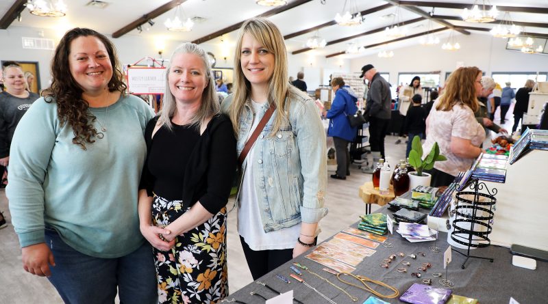 Three people pose for a photo at a craft market.