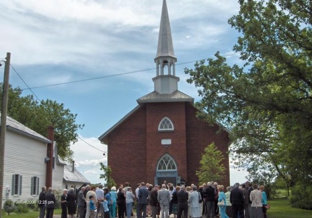 A photo of people standing outside a church.