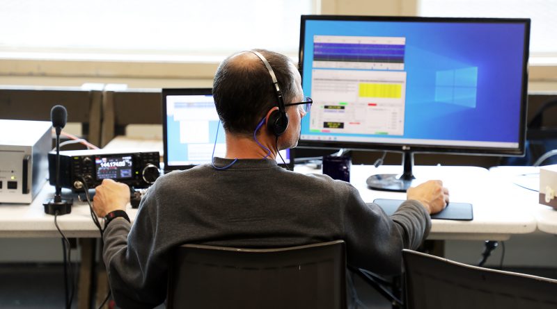 A man operates a radio by computer at a desk.