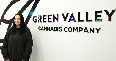 A person poses in front of the Green Valley logo.