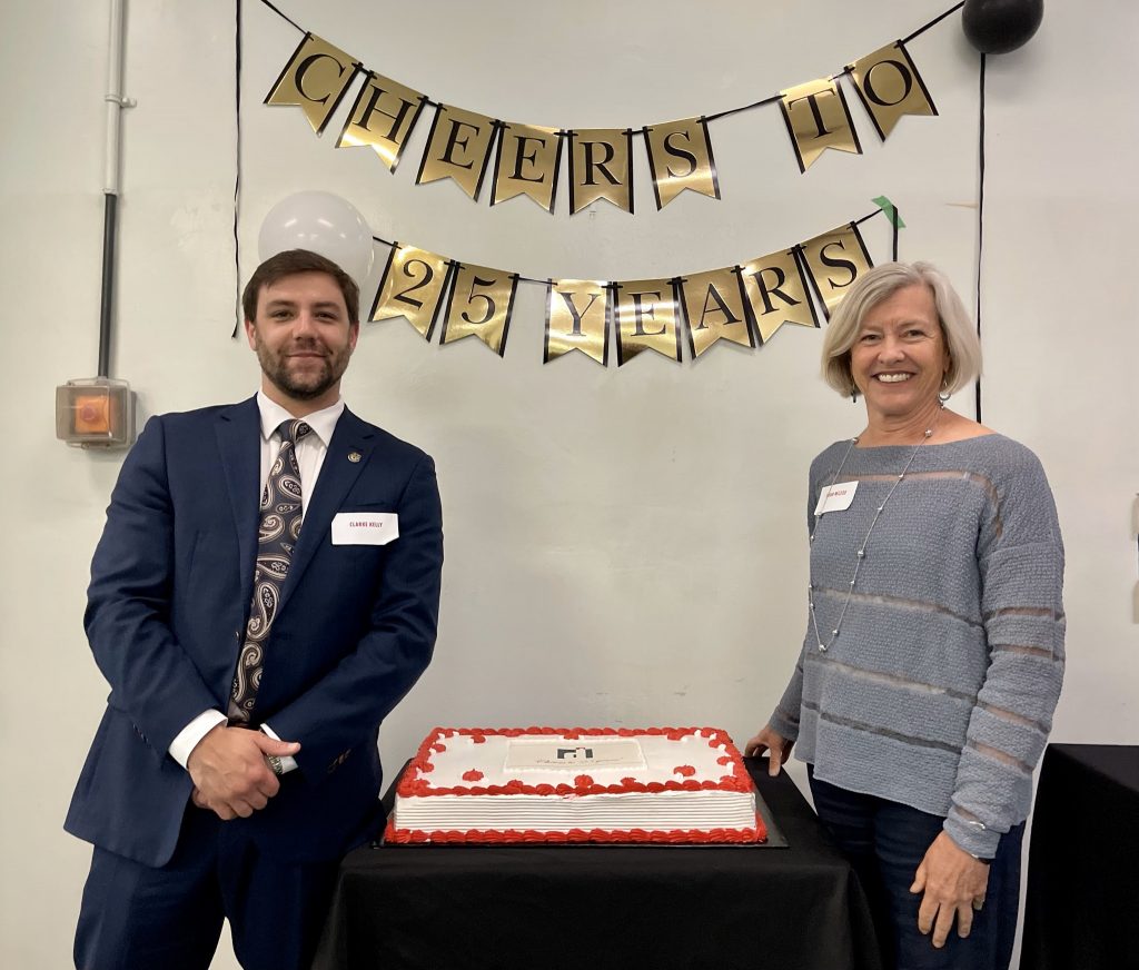 Two people stand beside a cake.