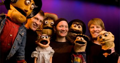 A photo of people surrounded by puppets.