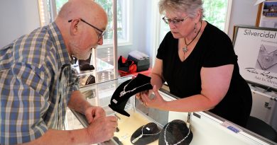 A woman shows a man some of her jewelry work.