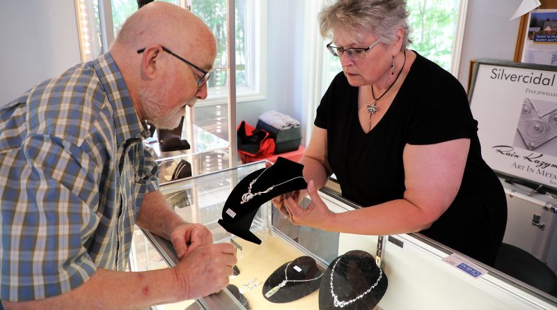 A woman shows a man some of her jewelry work.