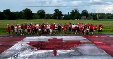 People pose around a Canada Day flag painted on a road.
