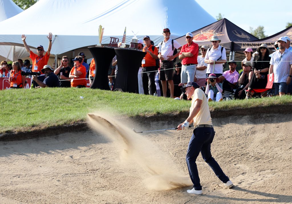 A man blasts out of a sandtrap.