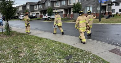 Firefighters walk down a street.