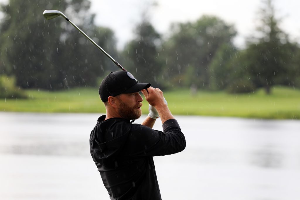 A hockey player watches his golf shot.